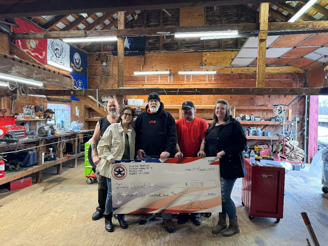 The Combat Customs crew in the shop holding a banner