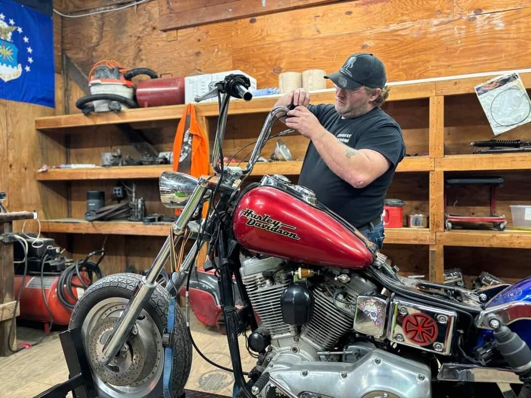 Veteran working on a motorcycle at the shop bench