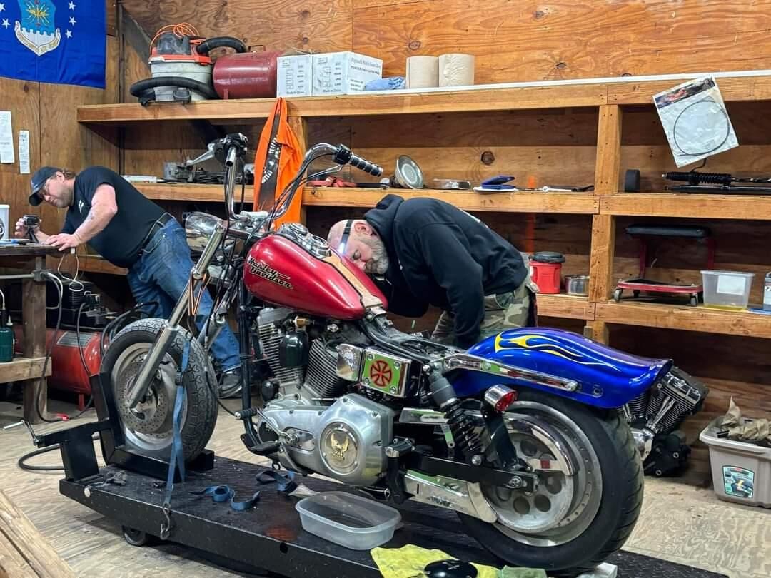 Two veterans working together on a motorcycle in the Combat Customs shop